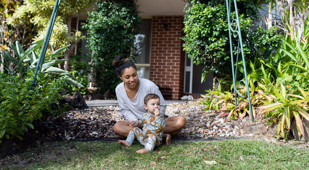 Mother and her young child sitting on the steps outside their home